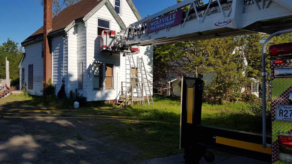 Aerial tower ladder bucket extended against house scrub area