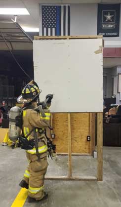 Firefighter with halligan working on pulling sheetrock