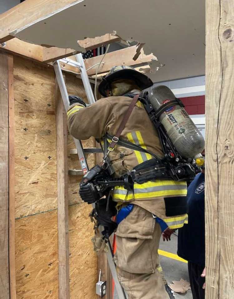 Firefighter ascends ladder in hallway training prop