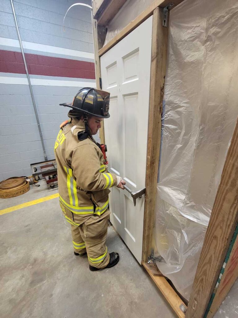 Firefighter practicing with halligan on door prop