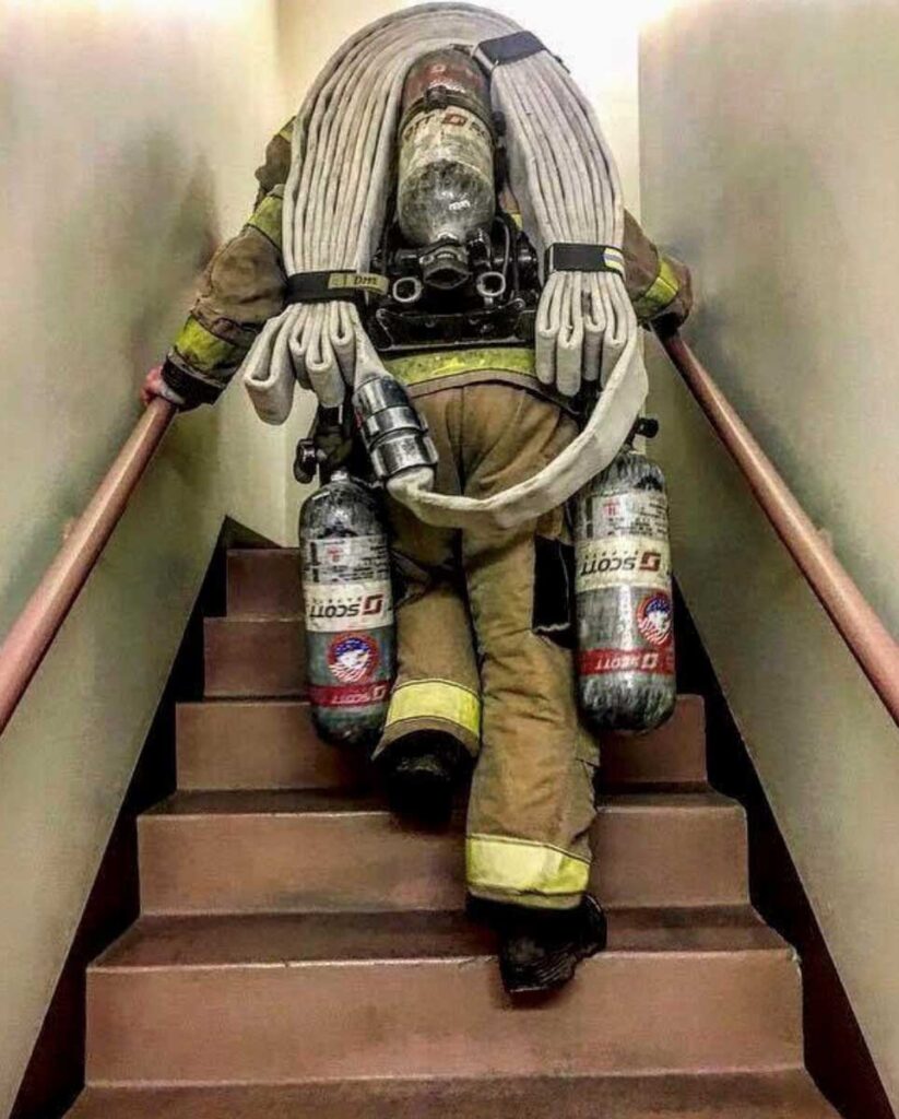 Firefighter on stairs carrying hoselines