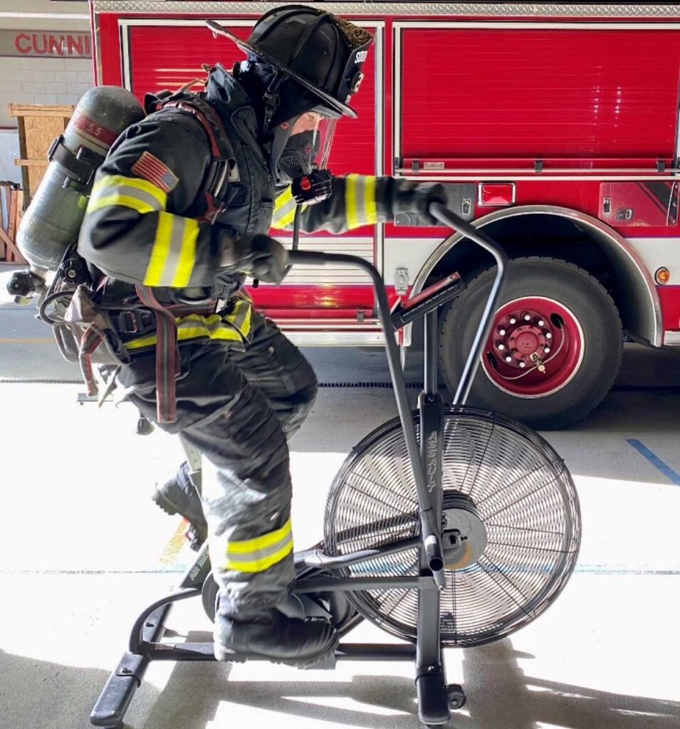 Firefighter fitness riding a stationary bike in gear