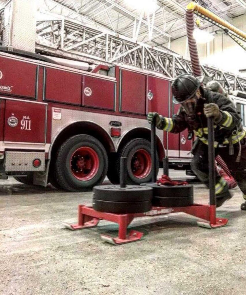 Firefighter in PPE pushing weight sled