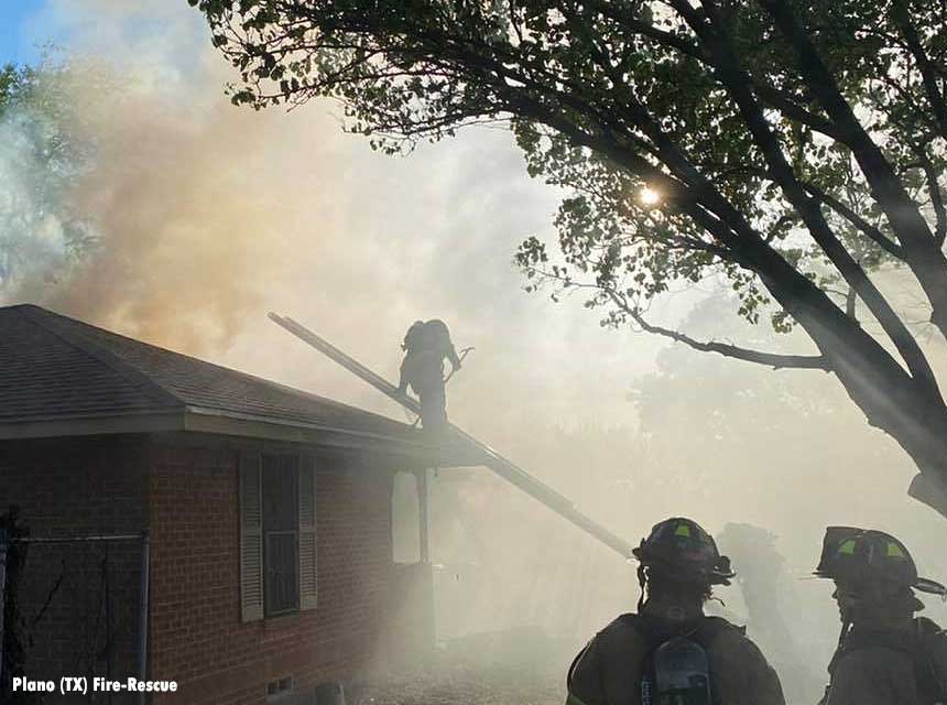 Plano firefighter on roof getting onto ladder amid smoke