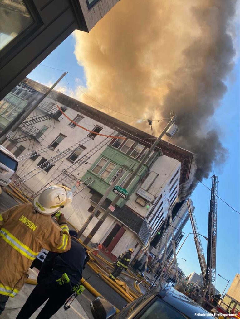 Smoke plume and ladders and Philly fire chief at fire