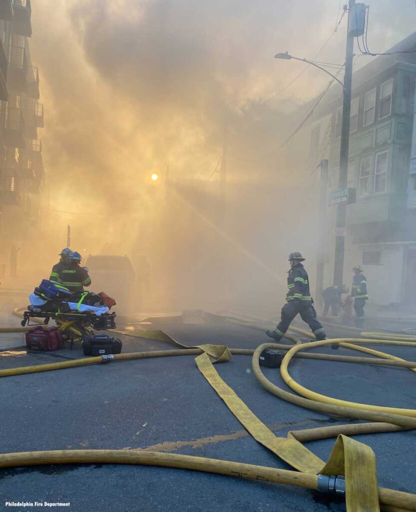 Firefighter strides across large diameter hoselines at Philadelphia fire