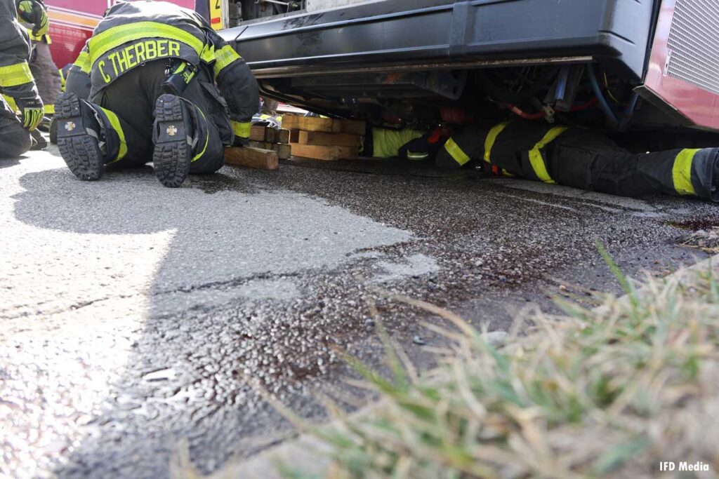 Firefighters work to rescue man pinned underneath INDYGO bus