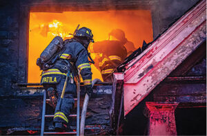 Firefighter on a turntable with flames behind him