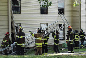 Firefighters with ladder on exterior of building