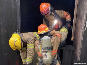 Firefighters hand a down firefighter out a simulated window during training