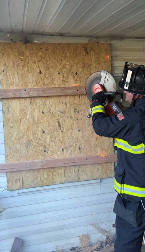 Firefighter using a K-12 saw to cut bolt heads on board