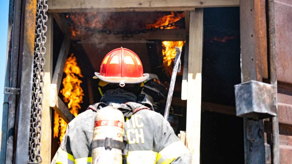 Firefighter in red helmet with fire in background