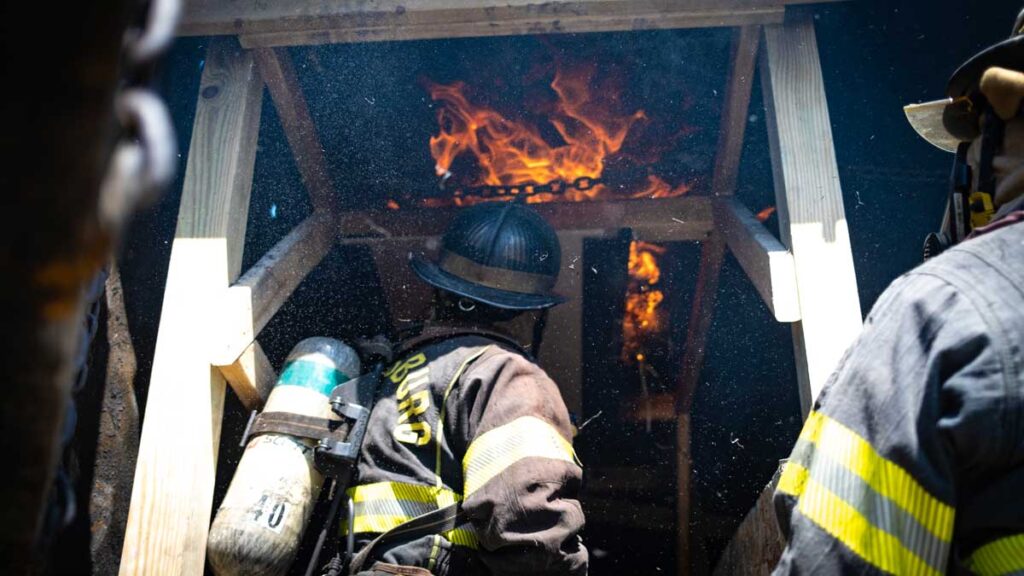 Firefighters look up at flames