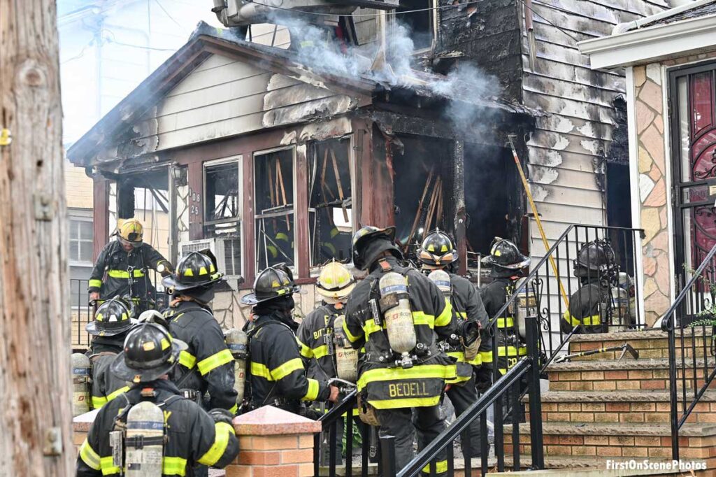 Firefighters outside front of burning home in Queens with melted siding