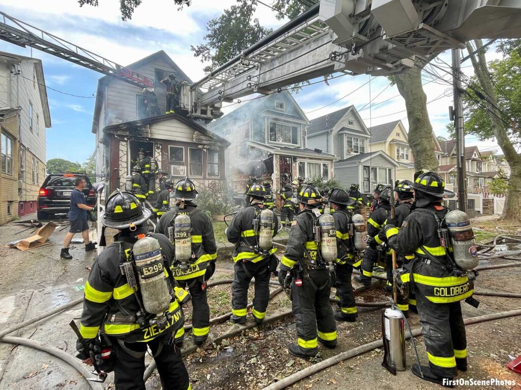 Firefighters underneath tower ladder and aerial at Queens fire