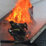 Firefighter on a roof with flames venting