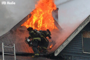 Firefighter on a roof with flames venting