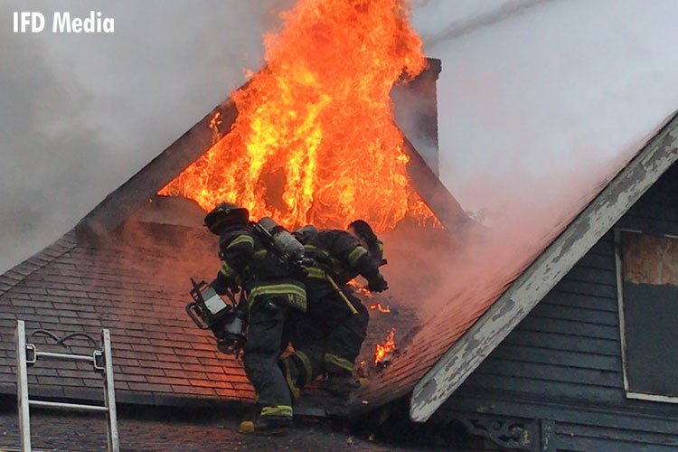 Firefighter on a roof with flames venting