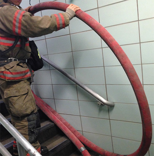 Firefighter moving a line up the stairs